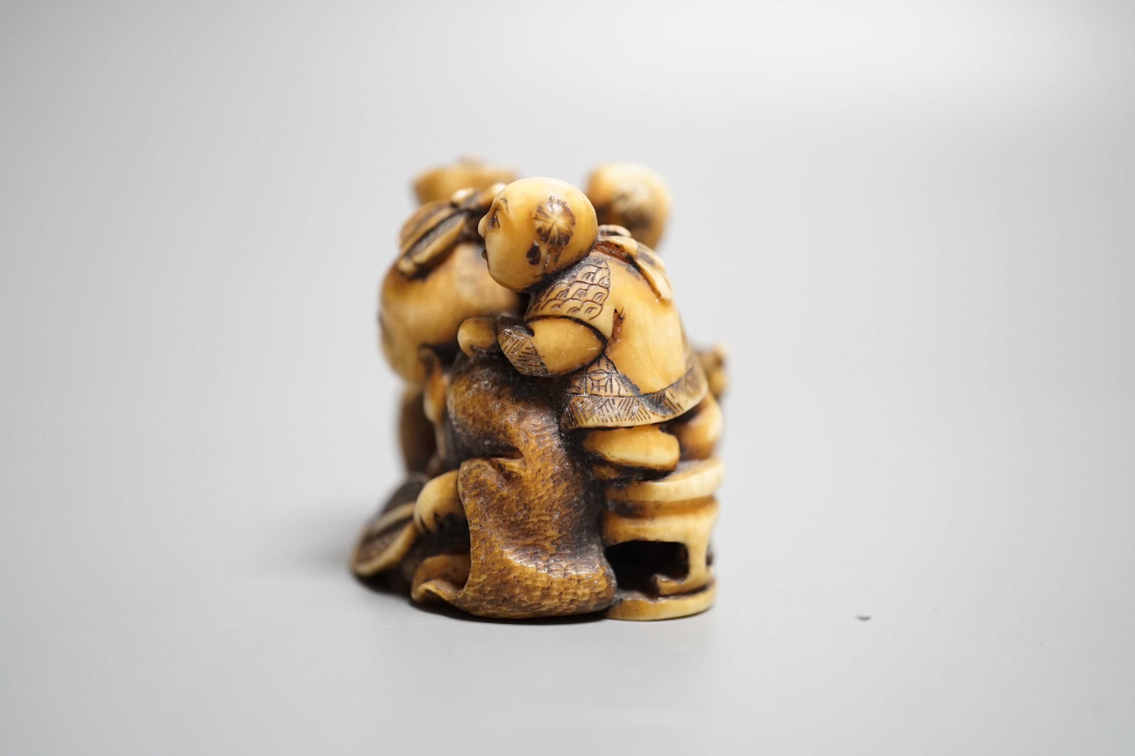 A Japanese ivory netsuke of Hotei with three boys, Meiji period, signed, width 4cm